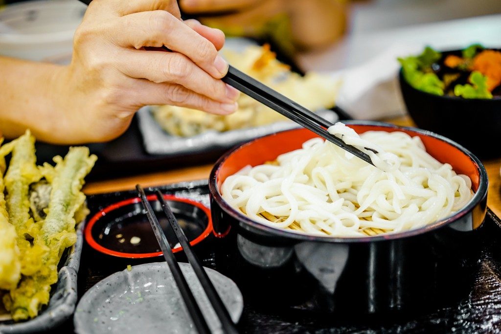 women hand using chopstick eat noodle