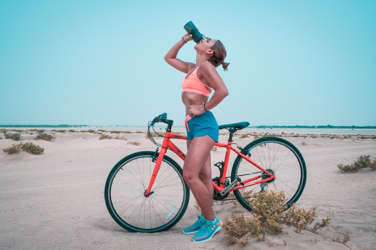 a woman drinking mineral water after biking activity